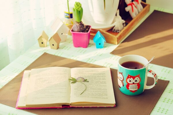 Przytulny stół, na którym leży otwarta książka i filiżanka herbaty