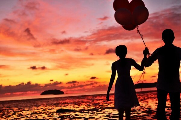 Couple goes with balloons at sunset