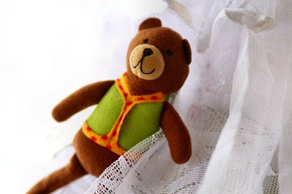 Teddy bear in a vest on a white cloth