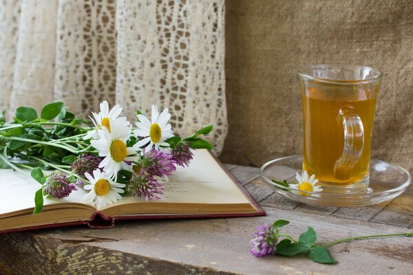 Eine Tasse Tee auf einem Tisch mit Blumen auf einem Buch