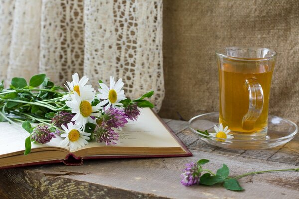 A mug of tea on the table with flowers on the book