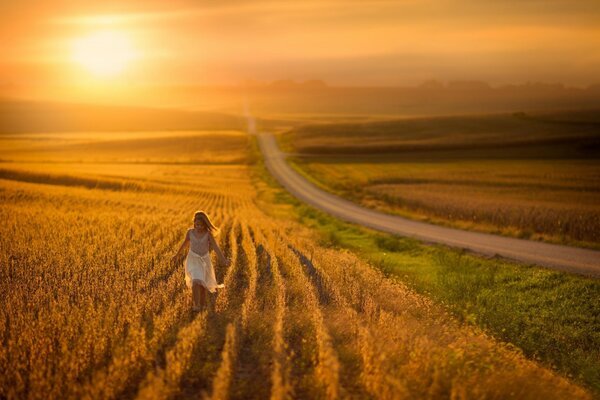 Fille court sur le champ dans les rayons du coucher du soleil