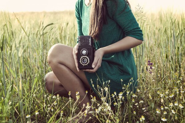 Chica con cámara en el fondo de las hierbas del Prado