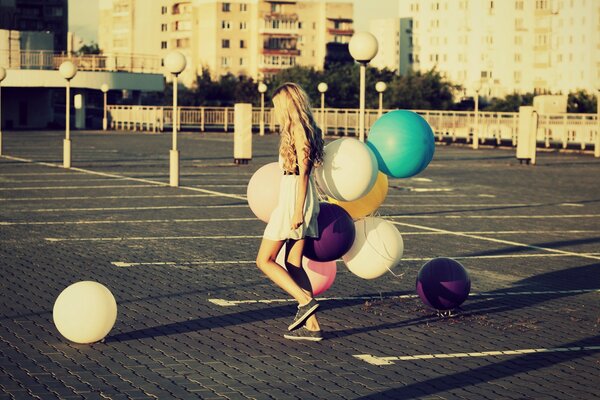 Una niña camina por la calle sosteniendo un montón de globos en la mano