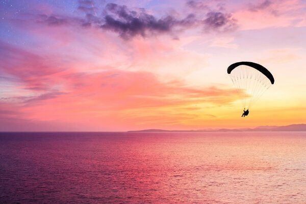 Beautiful sunset on the sea with a skydiver