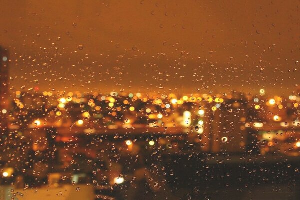 Misha regarde par la fenêtre à la pluie qui tombe sur la ville de nuit