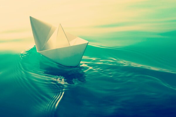Un barco de papel navega por el agua real