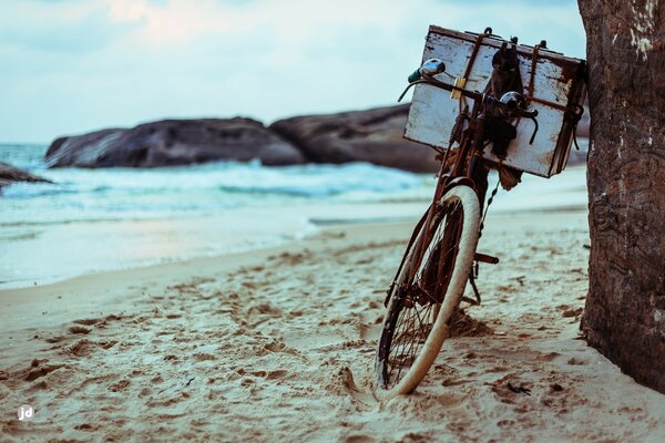 An old bicycle on the beach against the background of the sea and rocks