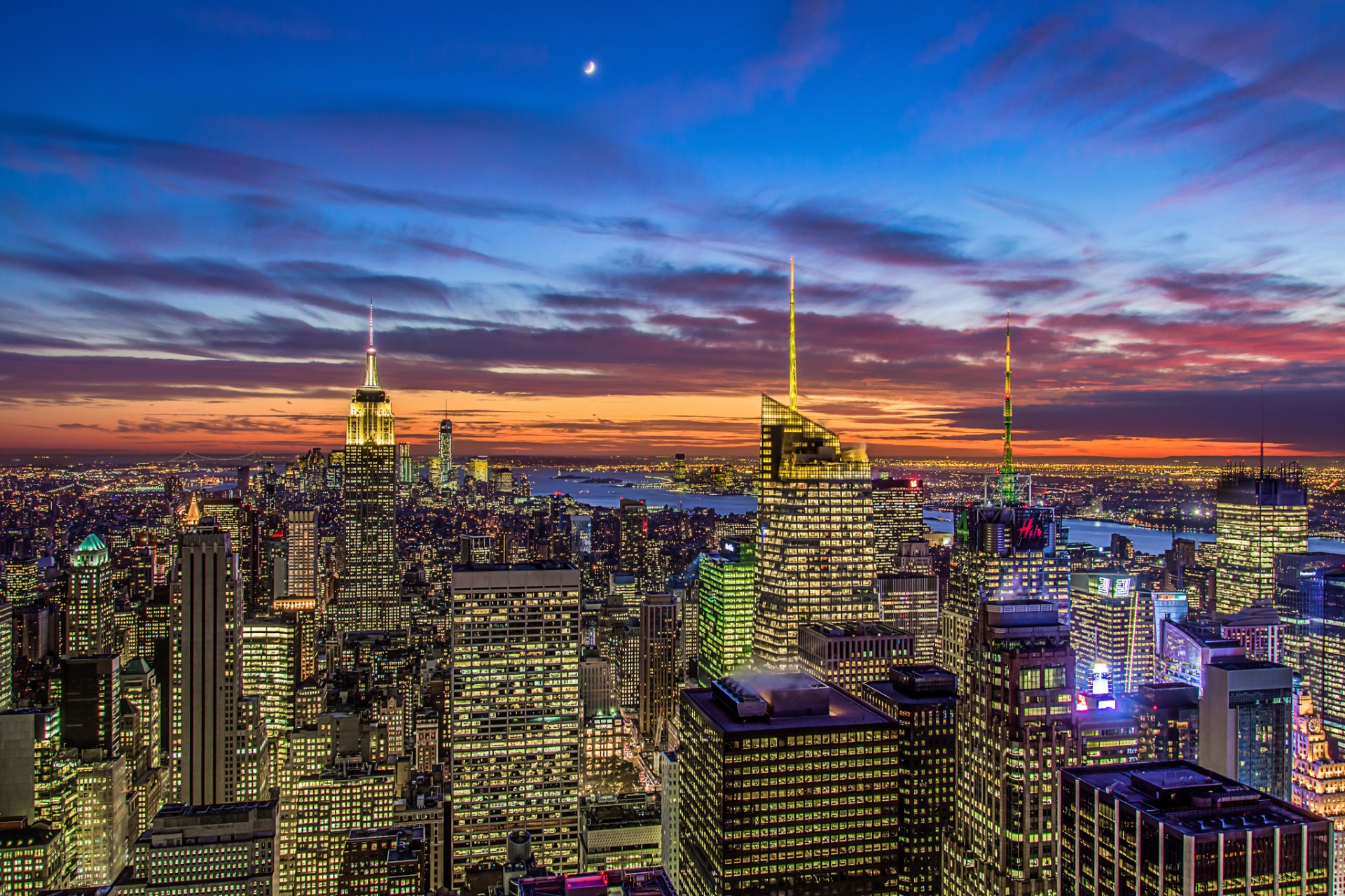 nowy jork usa manhattan empire state building dzielnica teatralna empire state building miasto panorama wieczór widok drapacze chmur budynki domy wieżowce światła pomarańczowy zachód słońca niebieski niebo chmury księżyc miesiąc