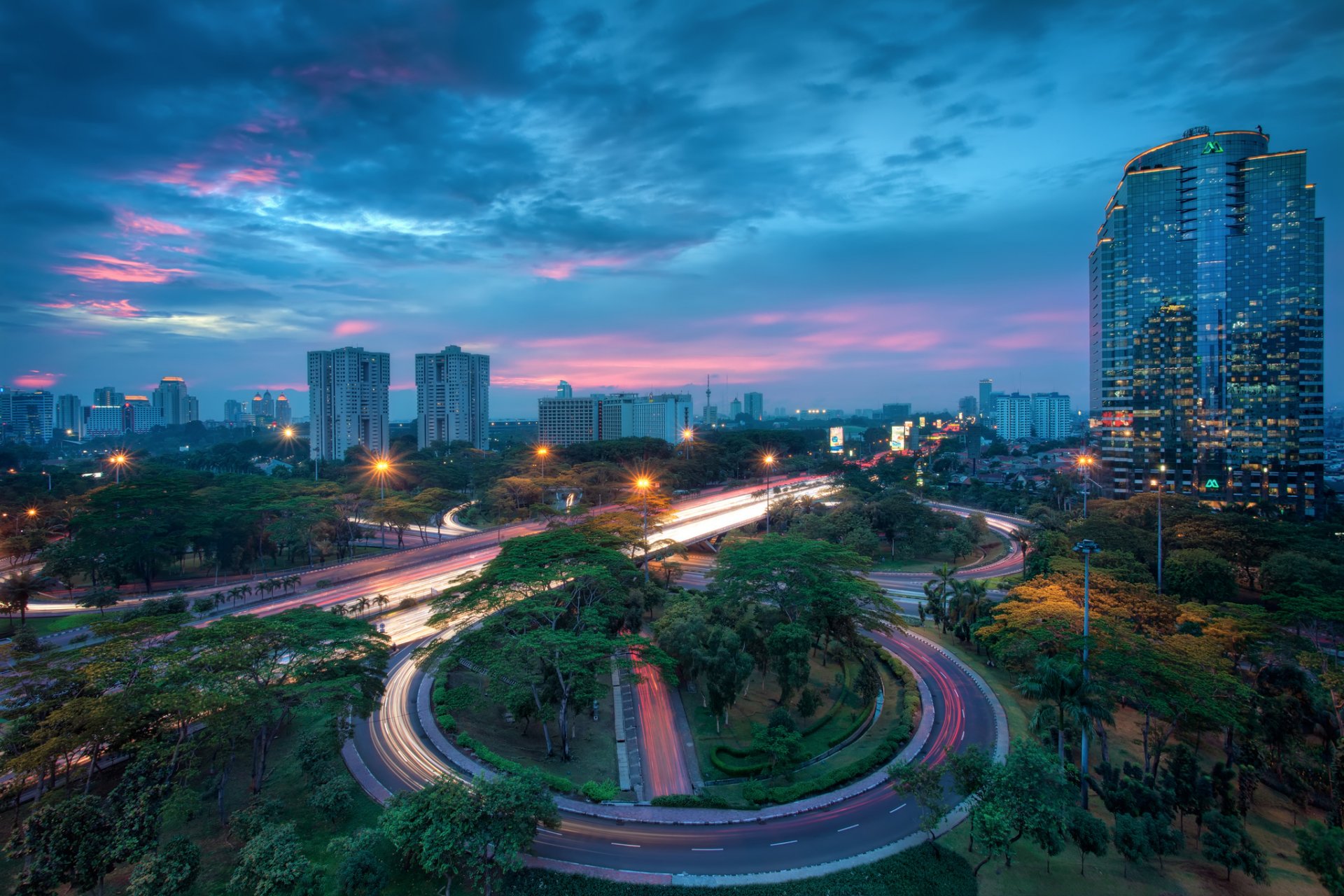 indonesien jakarta stadt hauptstadt metropole häuser gebäude wolkenkratzer abend himmel wolken beleuchtung lichter laternen bäume verkehr belichtung