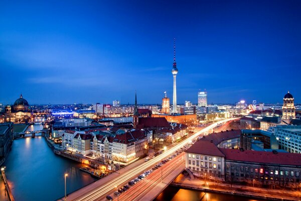 Panorama nocnego Berlina z mostem nad Tamizą i domami z wieżą telewizyjną w tle