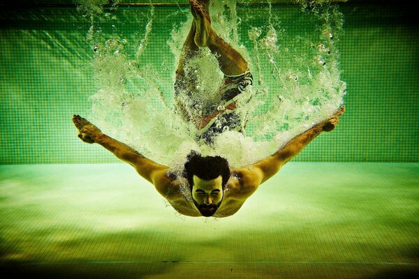 Athletic man dives into the pool