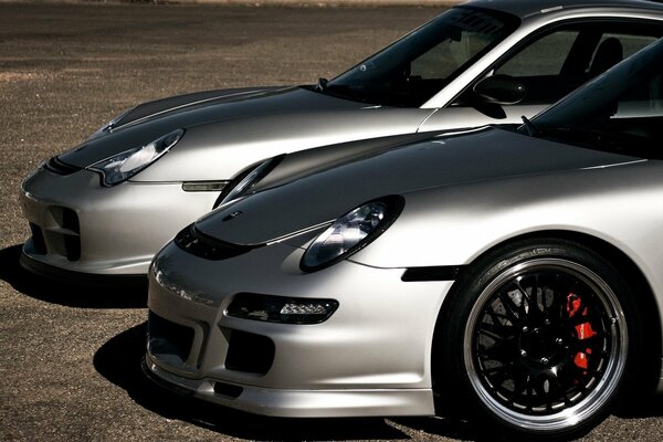 Two grey Porsche cars are standing next to each other