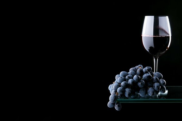 Rotwein mit Trauben auf schwarzem Hintergrund
