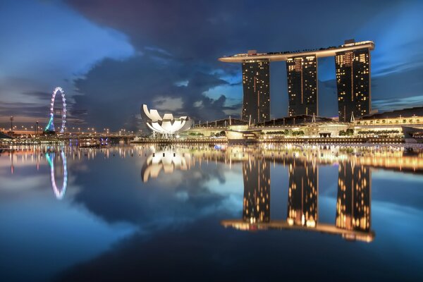 Water reflects the light of buildings and Ferris wheels