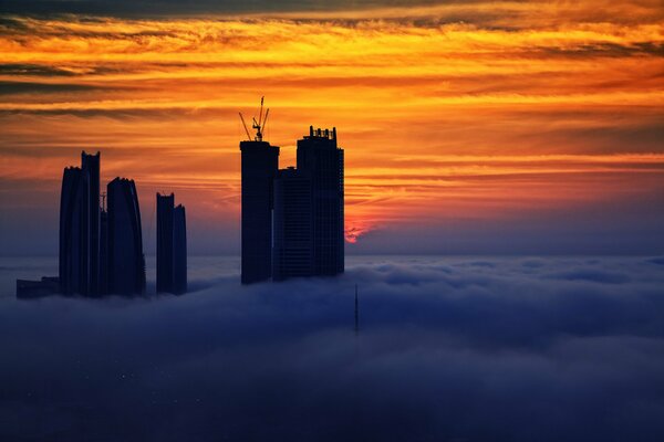 Hauts bâtiments des Émirats arabes Unis au coucher du soleil dans le brouillard