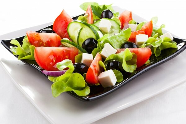 Ensalada griega en un plato negro sobre un plato blanco