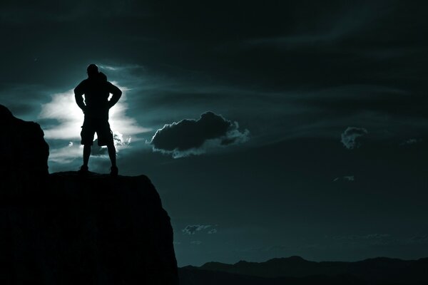 The night sky and the man on the ledge of the mountain