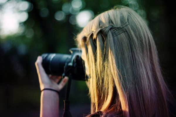 Blondes Mädchen fotografiert die Natur mit Haarspangen und einem geflochtenen Zopf