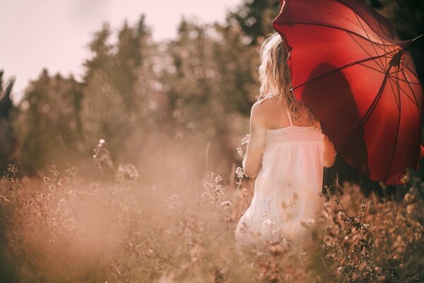 Una chica con un vestido blanco y un paraguas rojo entre las flores