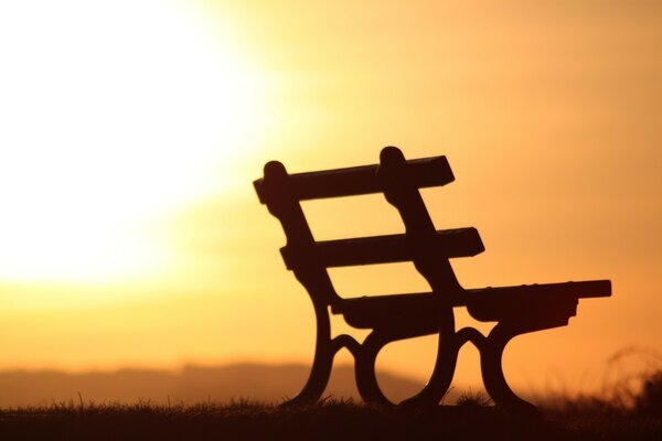 Sagoma di una panchina contro un tramonto arancione