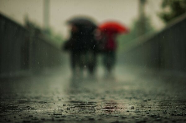 Menschen mit Schirmen bei Regen im Hintergrund