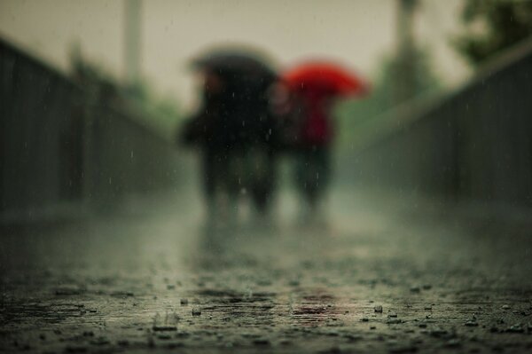 Люди с зонтами во время дождя на заднем плане
