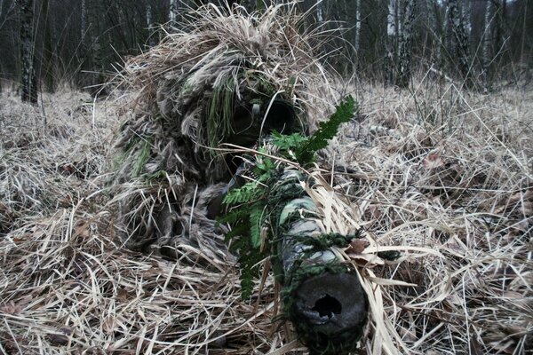 Francotirador con rifle en camuflaje disfrazado