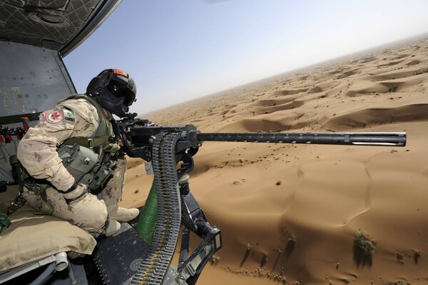 A man in a helicopter with a heavy machine gun