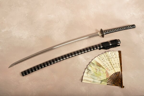Photos d une épée katana allongée à côté d un ventilateur