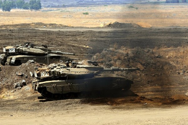 Czołgi wojskowe toczą się po pustyni