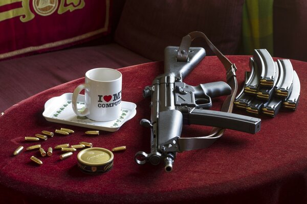 On the table is a small tray, a mug, weapons, spare discs