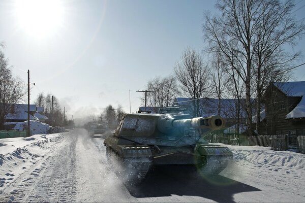 Im Winter fährt ein Panzer auf der Straße durch das Dorf