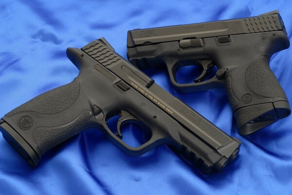 Two black police pistols on a background of blue fabric