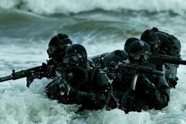 Militares con armas en el mar entre las olas