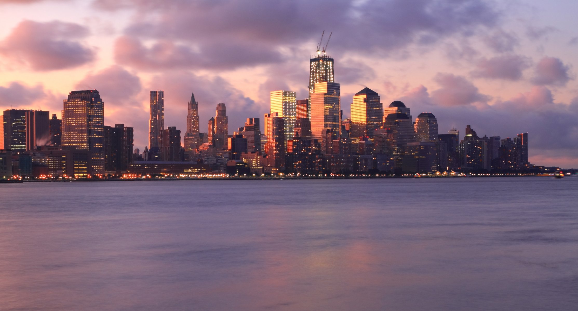 usa new york metropole gebäude wolkenkratzer hintergrundbeleuchtung lichter fluss abend rosa sonnenuntergang himmel wolken wolken