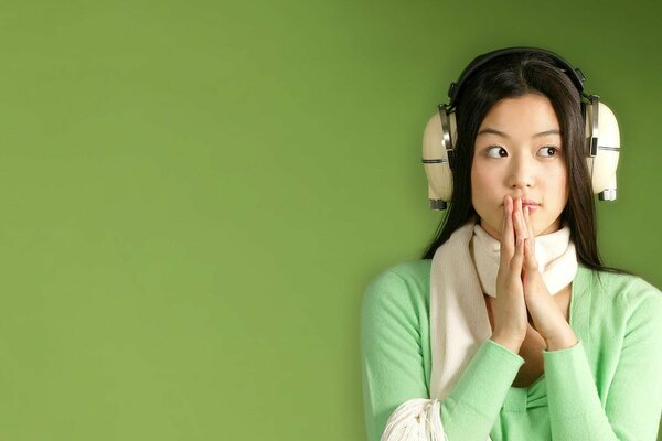 Brunette girl with headphones on a green background