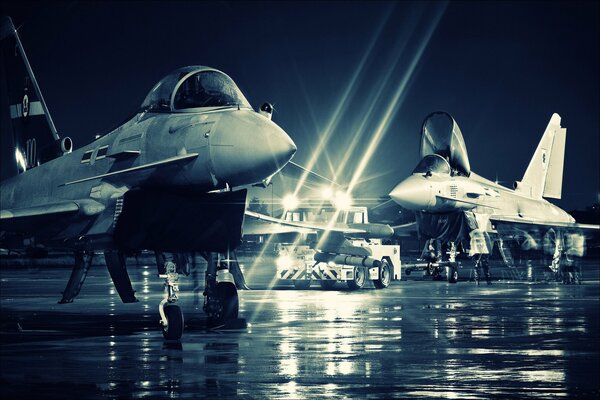 An airplane at an airfield among other planes under the light of searchlights