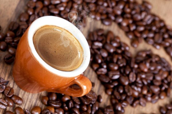 Tazza di caffè con schiuma vicino ai chicchi di caffè