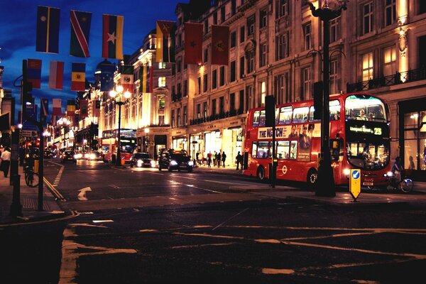 Autobuses, coches, personas en una calle nocturna en el centro de Londres