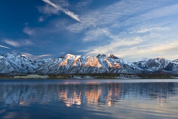 Montañas en la nieve en la orilla del lago