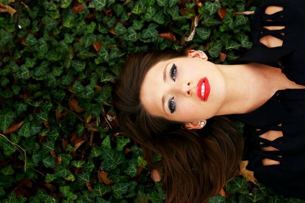 A girl with a beautiful face on a background of leaves