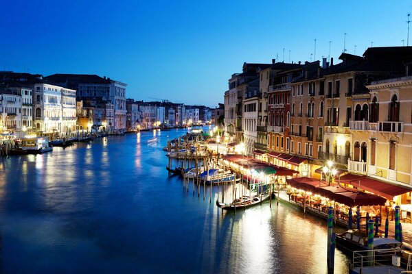 The glowing shores of Venice, gondolas on the blue river