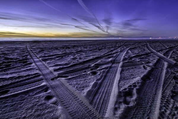 Traces de la bande de roulement des pneus sur le sable avec un beau ciel