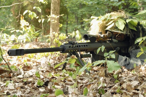 Sniper avec fusil dans la forêt au camouflage