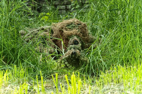 A sniper is sitting in ambush in camouflage