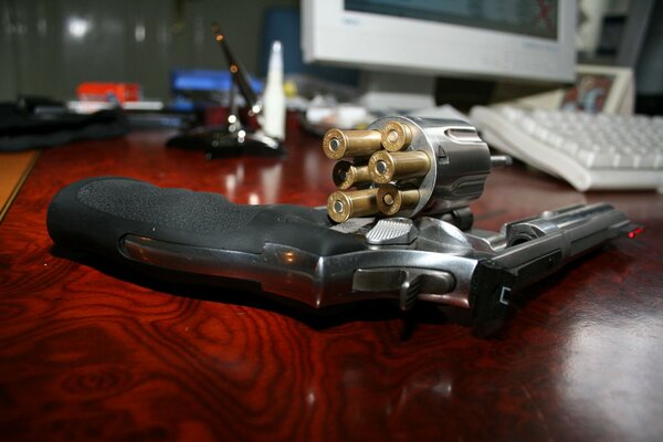 A pistol with a drum and bullets on the table