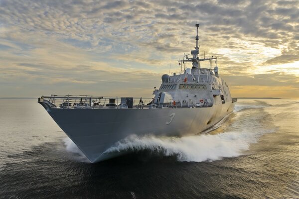 A ship cutting through the waves at sunset