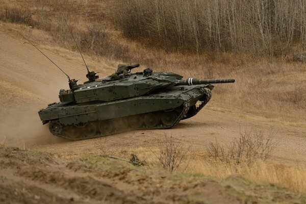 Военный танк едет по дороге