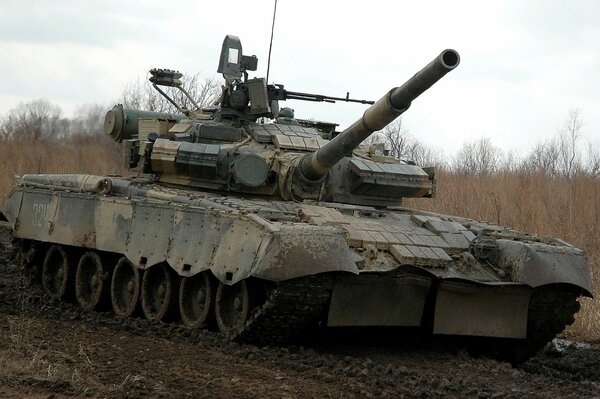 A military tank is driving on a muddy road